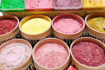 Row of colorful bowls filled with different colored powders