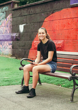 Aboriginal woman sitting on a park bench with a painted flag in the background