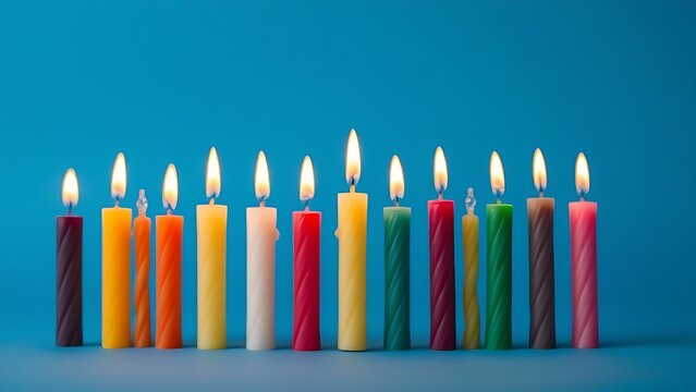 A row of colorful tapered candles with glowing flames creates a warm and festive ambiance.