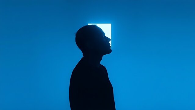 A minimalist silhouette of a person holding a glowing rectangular object in cool blue tones.