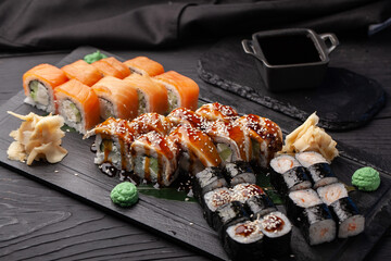 Delicious sushi platter featuring assorted rolls and garnishes served on a black slate plate