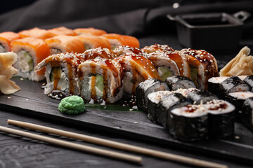 Delicious sushi assortment on a black slate platter featuring rolls, wasabi, and ginger arranged artistically for a culinary delight