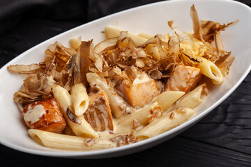 Delicious salmon pasta served with fresh herbs and sliced fish flakes in a white bowl