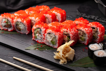 Freshly made sushi rolls with vibrant toppings served on a black platter during a culinary experience