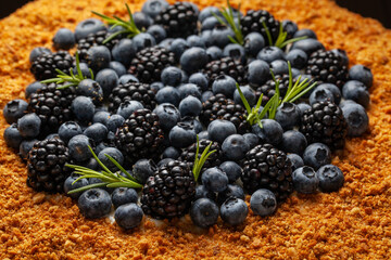 Dessert display featuring blueberries and blackberries garnished with fresh herbs on a crumbly base at a summer gathering