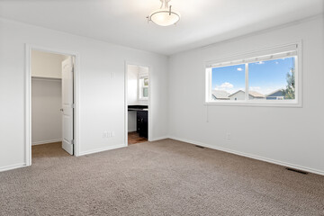 Large, empty room with a window and a closet