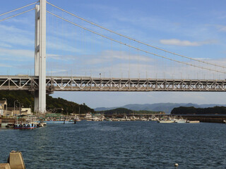 A panoramic view of the fishing village beneath the suspension bridge. This bridge, the Seto Ohashi Bridge, is a landmark of Western Japan.