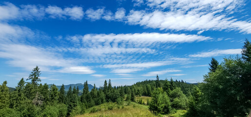 A stunning mountain landscape with lush greenery under a vibrant blue sky with wispy clouds, ideal for travel, nature, and outdoor lifestyle campaigns.