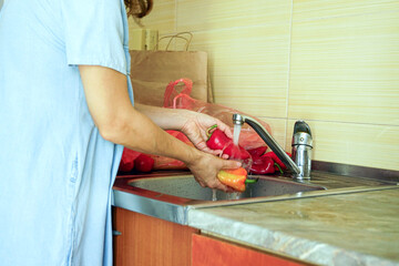 Woman cleaning sweet paprika before slicing for healthy homemade recipe. Showcasing cooking preparation, use of fresh seasonal ingredients, plant-based diet, food safety, home cooking, vegan nutrition