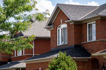 Row of suburban houses with gable roofs and brick walls.