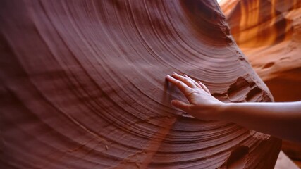 Hand sliding on the smooth surface of a sandstone formation inside Antelope Canyon, Arizona, creating a tactile exploration of nature's beauty - Powered by Adobe