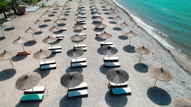 Picturesque drone view of a beach with turquoise waters and organized sun loungers in Orikum, Vlore, Albania