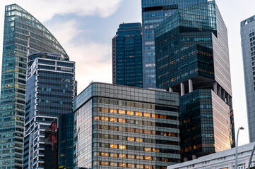Urban architecture and illuminated workspaces in Singapore financial district at dusk, Asia