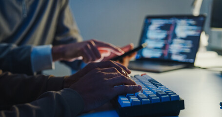 Closeup team adult male engineer collaborate on robotic hand project use AI code solutions machine learn at tech workspace night. Artificial intelligence interface collaboration prototype development.
