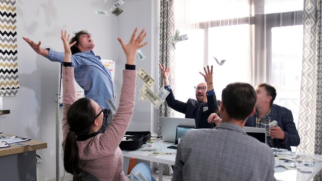 Economists celebrate an unexpected financial success in the office of the company. Happy people throw up money,