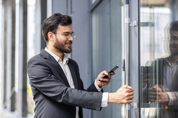 Professional man in business attire accessing office using smartphone for secure entry.