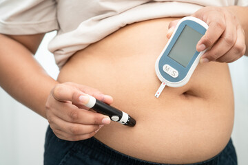 Asian woman injecting herself diabetes injecting insulin in stomach at home.