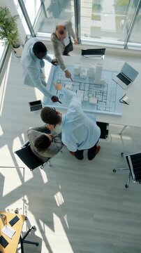 A Collaborative Meeting: Professionals Engaged in Strategic Planning Over Architectural Models and Design Blueprints in a Modern Workspace