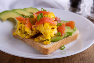 scrambled eggs with fish and avocado on toast. Delicious breakfast.