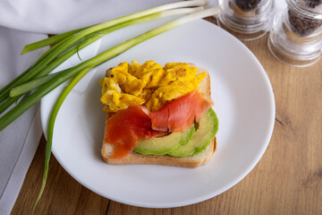 scrambled eggs with fish and avocado on toast. Delicious breakfast.