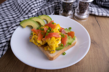 scrambled eggs with fish and avocado on toast. Delicious breakfast.