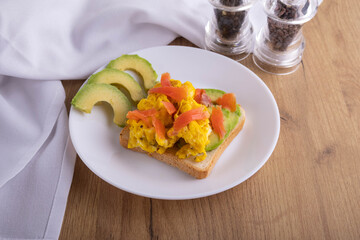 scrambled eggs with fish and avocado on toast. Delicious breakfast.