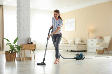 Fototapeta premium Woman cleaning floor with vacuum cleaner at home