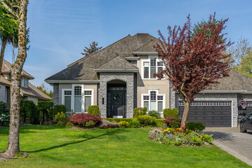 Two story stucco luxury house with nice spring blossom landscape in Vancouver, Canada, North America. Day time on May 2025.