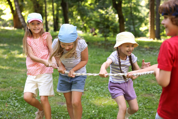 Cute little kids playing tug of war in park
