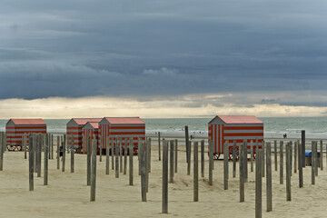 Row of red and gray beach huts at sunset at De Panne, Belgium.
