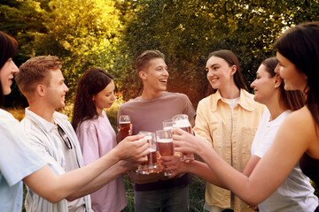 Group of happy friends with pizza clinking glasses of beer outdoors