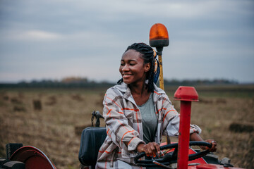 Smiling farmer driving a tractor in a harvested field © La Famiglia