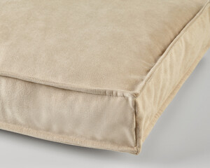Beige velvet cushion resting on a neutral background