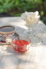 Berry jam in a glass bowl on a table in a sunny summer garden