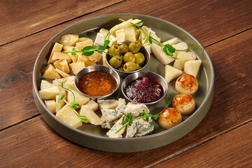 Cheese plate with honey, jam, olives and snacks decorating a wooden table