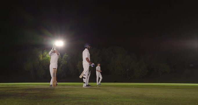 Diverse male team bowling at night batsman missing drive keeper breaking wicket for stumping