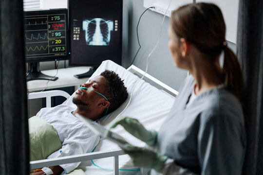 High angle selective focus of doctor checking heart rate, blood pressure, oxygen saturation and breath rate of patient after serious surgery - Powered by Adobe