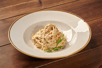 Creamy spaghetti carbonara with parmesan and herbs on rustic wooden table