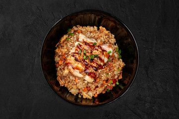 Delicious teriyaki chicken with rice and sesame seeds in a black bowl