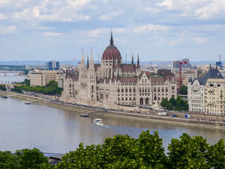 Fototapeta premium Aerial view of grand neo-Gothic parliament building by riverside, suitable for illustrating politics, travel destinations, and historic architecture concepts.