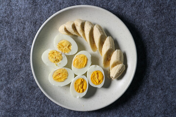 Healthy food. Boiled eggs and sliced bananas on a plate.