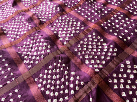 This vine gaji fabric showcases intricate white bandhani dots, gracefully arranged to highlight its artisanal charm.
