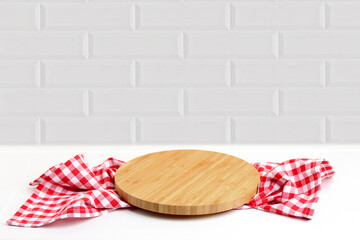 Round cutting board with checkered kitchen towel on white table