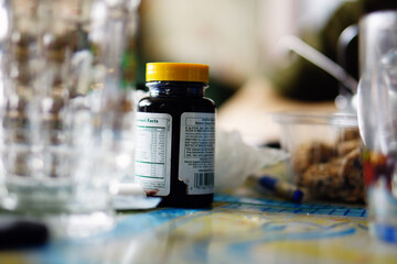 Supplement Bottle on Cluttered Table – Everyday Still Life with Nutritional Product and Domestic Ambiance