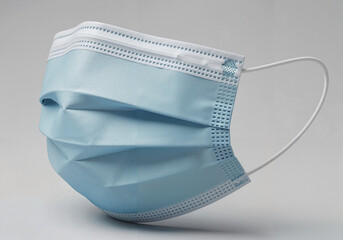 Blue surgical mask with white ear loops on a light background  