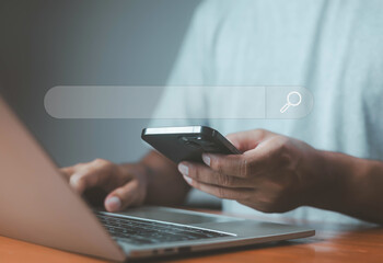 Man using smartphone and laptop with a transparent search bar interface, symbolizing internet browsing, online research, and digital search technology.