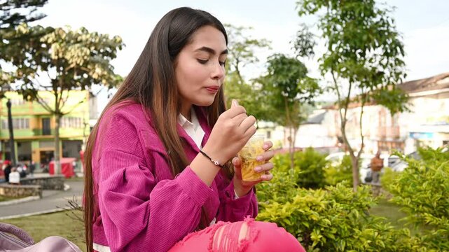 Latin woman enjoying a refreshing mango biche in a park in Latin America, video 4k real time