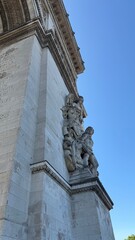 Obraz premium Paris, France - July 4 2025: Detailed view of the ‘Le Triomphe de 1810’ sculpture on the Arc de Triomphe in Paris, France, under a clear blue sky.