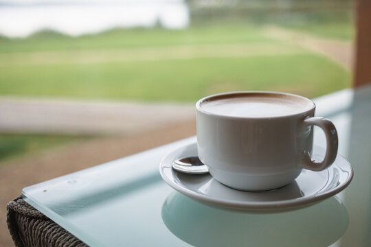 Close-up of a latte coffee on a glass garden table