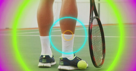 Displaying lower legs wearing socks, navy shoes on tennis court, with racket, ball and neon rings